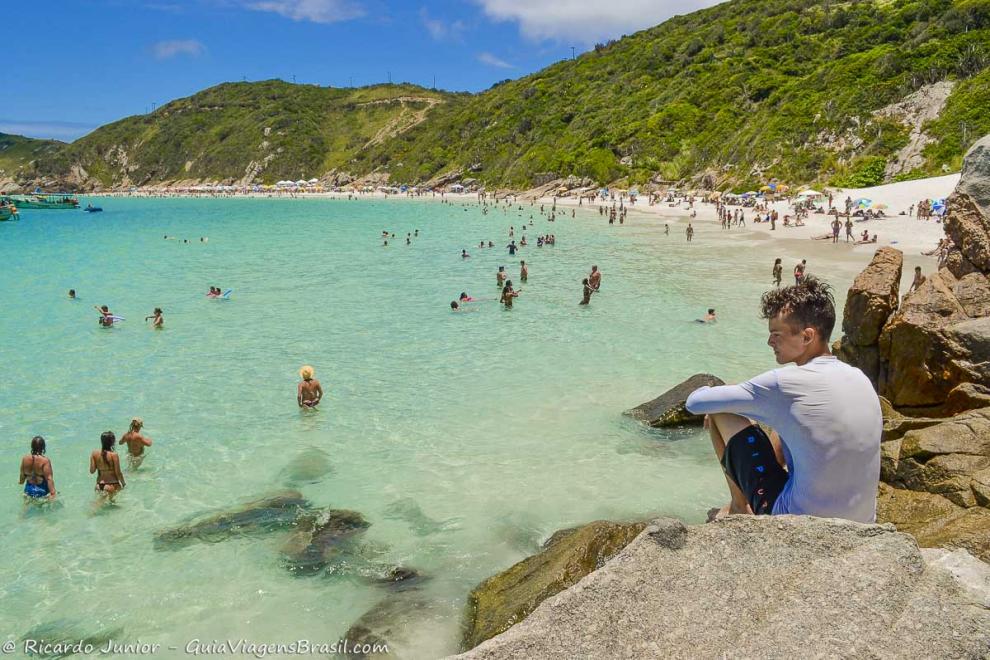 Imagem de um menino nas pedras curtindo o visual da Praia do Pontal do Atalaia.